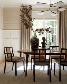 a dining room table with four chairs and a vase on top of it in front of a window