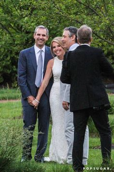 a group of people standing next to each other in a field with trees behind them