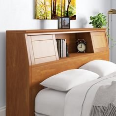 a bed with white sheets and pillows next to a wooden book shelf filled with books