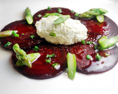 a white plate topped with beets covered in sauce and garnished with scallions