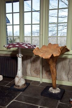 two wooden sculptures sitting next to each other in front of a window with large windows