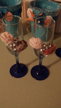 three wine glasses with seashells on them sitting on a counter next to other glassware