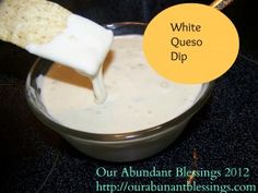 a bowl filled with white cheese dip next to a yellow sign that says, white queso dip