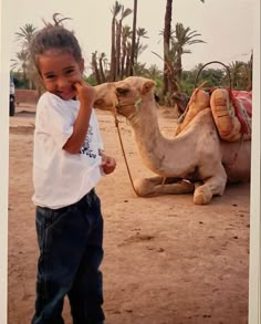 a little boy standing next to a camel