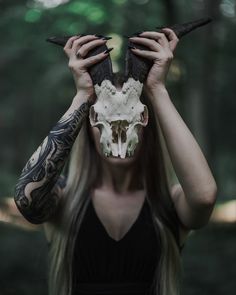 a woman covering her face with an animal skull