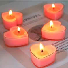 six lit candles sitting on top of a piece of paper next to an open book