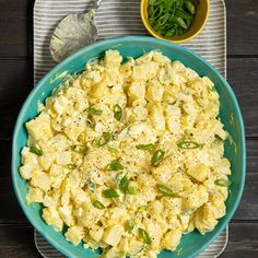 a blue bowl filled with scrambled eggs next to a small yellow bowl full of green beans