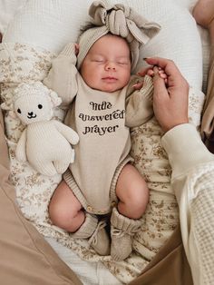 Celebrate your little miracle with our beautiful beige embroidered knit romper, designed to keep your baby nice and cozy! Crafted from soft, breathable fabric, this romper features long sleeves for extra warmth, making it perfect for any season. The standout detail of this romper is the sweet embroidery that reads "little answered prayer" in a lovely neutral brown hue, adding a heartfelt touch to your baby’s wardrobe. Designed with practicality in mind, the romper includes buttons for easy diaper changes, allowing you to tend to your little one effortlessly. The relaxed fit ensures plenty of room for movement, so your baby can crawl, wiggle, and explore with ease. Mix and match with our matching booties, beanie or topknot! Sweet Embroidery, Knit Bow, Ribbed Knit Bodysuit, Knit Romper, Knitted Booties, Toddler Bows, Family Outings, Knitted Romper