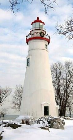 a white and red light house surrounded by snow