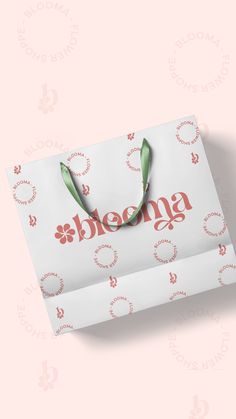 a white shopping bag with the word shema printed on it and a green ribbon