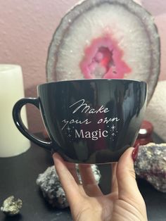 a person holding up a black coffee cup with writing on the side and pink inside