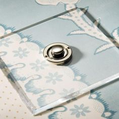 a button on a glass surface with blue and white wallpaper