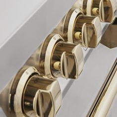 three brass handles on a white cabinet with mirrored glass door knobs in the middle