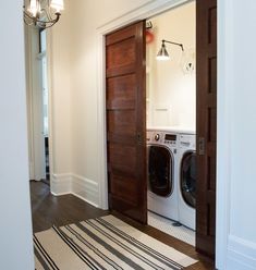 a washer and dryer are sitting in the entryway to a home with wood doors