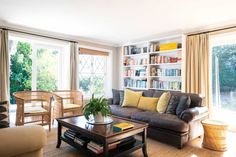 a living room filled with furniture and bookshelves next to a window covered in curtains