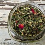 a jar filled with green tea sitting on top of a wooden table next to a red rose