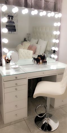 a white vanity with lights on it and a chair