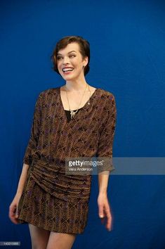 a woman in a brown dress standing against a blue background