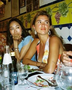 two women sitting at a table with plates of food