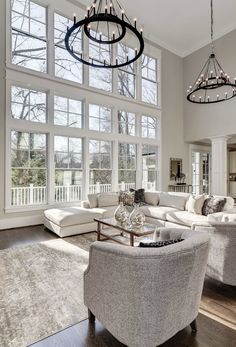 a living room filled with lots of furniture and large windows in the wall behind it