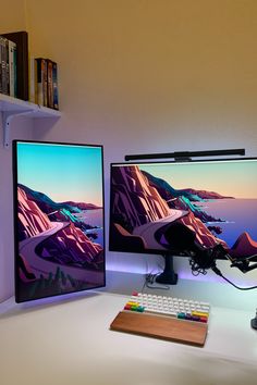 two computer monitors sitting on top of a desk