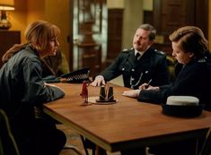 three people sitting at a table in uniform