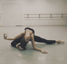 a woman in black is laying on the floor with her hands behind her head and legs spread out