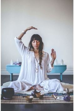 a woman sitting on the floor with her hands in the air