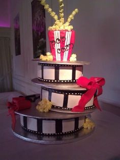 a three tiered cake decorated with popcorn and movie film strips is displayed on instagram