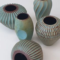 four vases are shown on a white surface