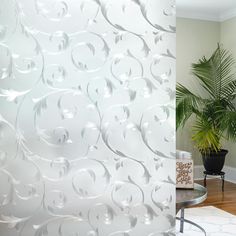 a living room with a plant in the corner and a white wallpaper behind it