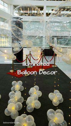 balloons are floating in the air on a black carpet with white lights and red carpet