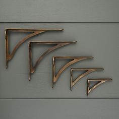 three metal shelf brackets on a gray wall