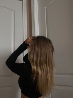 a woman standing in front of a door with her back turned to the camera and wearing a black top