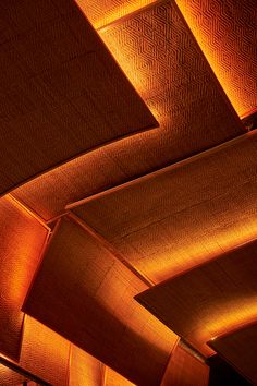 the ceiling is covered in orange lights and wood paneled panels with geometric designs on them