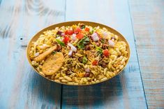 a bowl filled with rice and vegetables on top of a wooden table