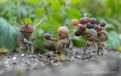 three little figurines are holding grapes in their hands and standing on the ground