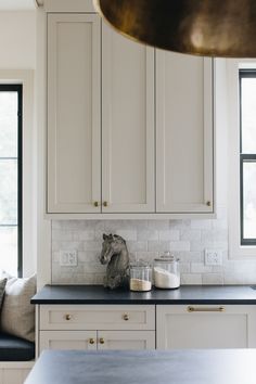 a kitchen with white cabinets and black counter tops in front of two large windows that look out onto the street