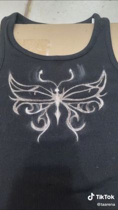 the back of a black tank top with white designs on it's chest and shoulder