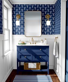 a bathroom with blue and white wallpaper, two sinks and a mirror on the wall