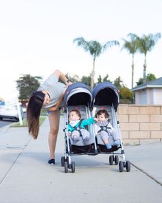 a woman pushing a stroller with two babies in it