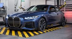 a blue car is parked in a garage with yellow and black stripes on the floor