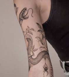 a woman's arm with a snake and flowers tattoo design on the left arm