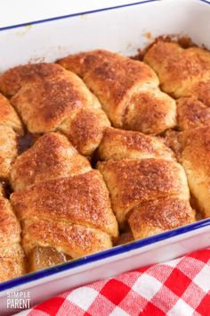 a casserole dish filled with cinnamon rolls on top of a red and white checkered table cloth