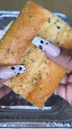 a person holding a sandwich in their hand with black dots on the outer half of it