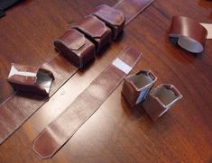 several pieces of brown leather sitting on top of a wooden table next to scissors and tape