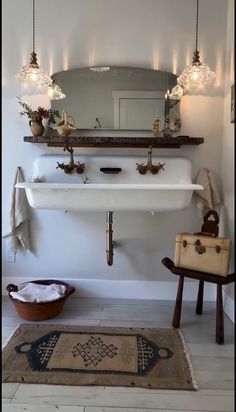 a white sink sitting under a bathroom mirror next to a wooden chair and rug in front of it