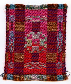 a red and blue rug with fringes on the bottom is shown in front of a white background