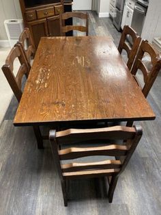 a wooden table and chairs in a room with hardwood flooring on the ground, next to an oven