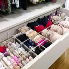 an open drawer with several pairs of shoes and purses in it on top of a wooden floor